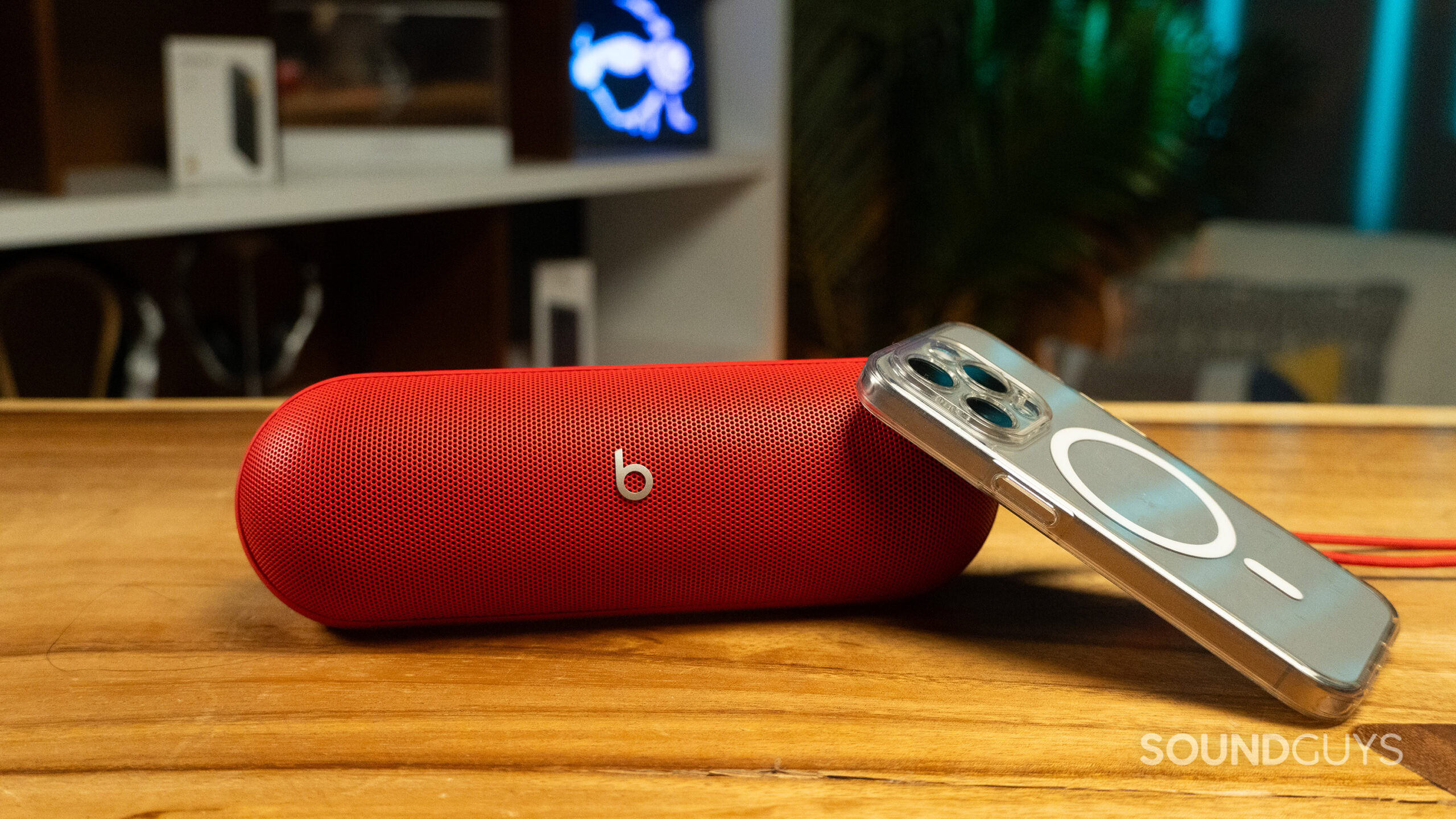Beats Pill on a table next to a phone The Beats Pill next to an iPhone 15 Pro.