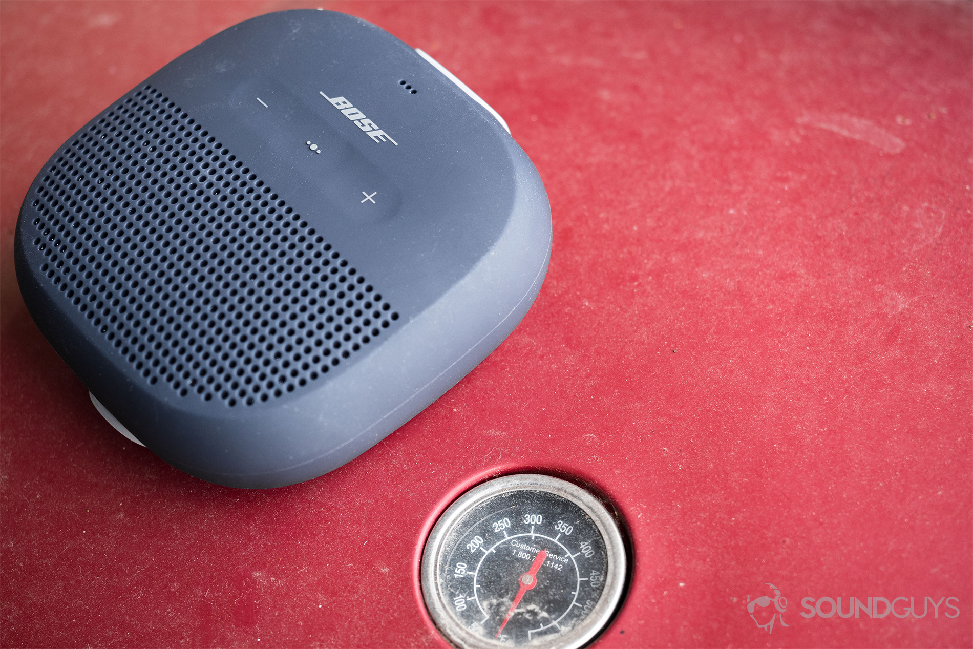 Bose_SoundLink Micro_ (4) SoundLink Micro on a red grill with the thermometer showing.