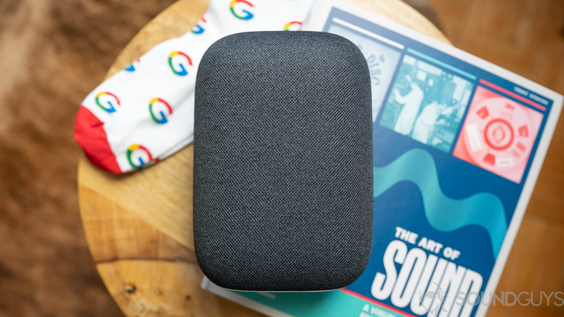 Google Nest Audio drivers Google Nest Audio on top of coffeetable with a book and pair of Google socks