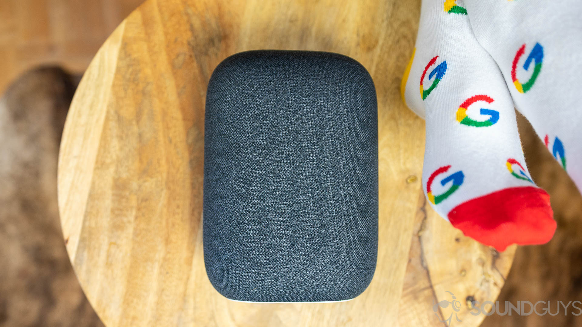 Google Nest Audio has rounded design Google Nest Audio in black next to person wearing Google socks.