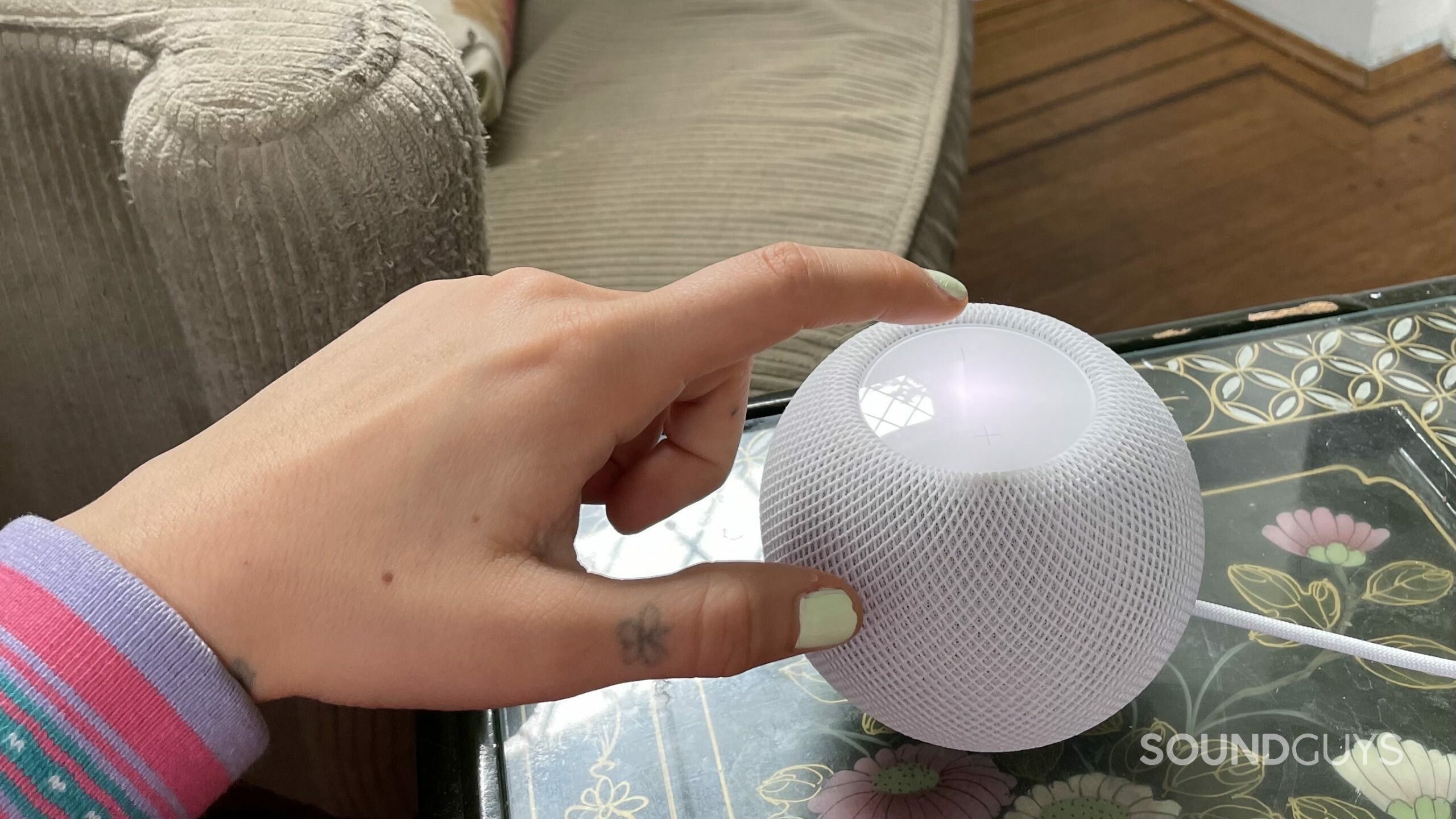 Apple Homepod mini hand use Womans hand about to tap the touchpad of the Apple HomePod mini.