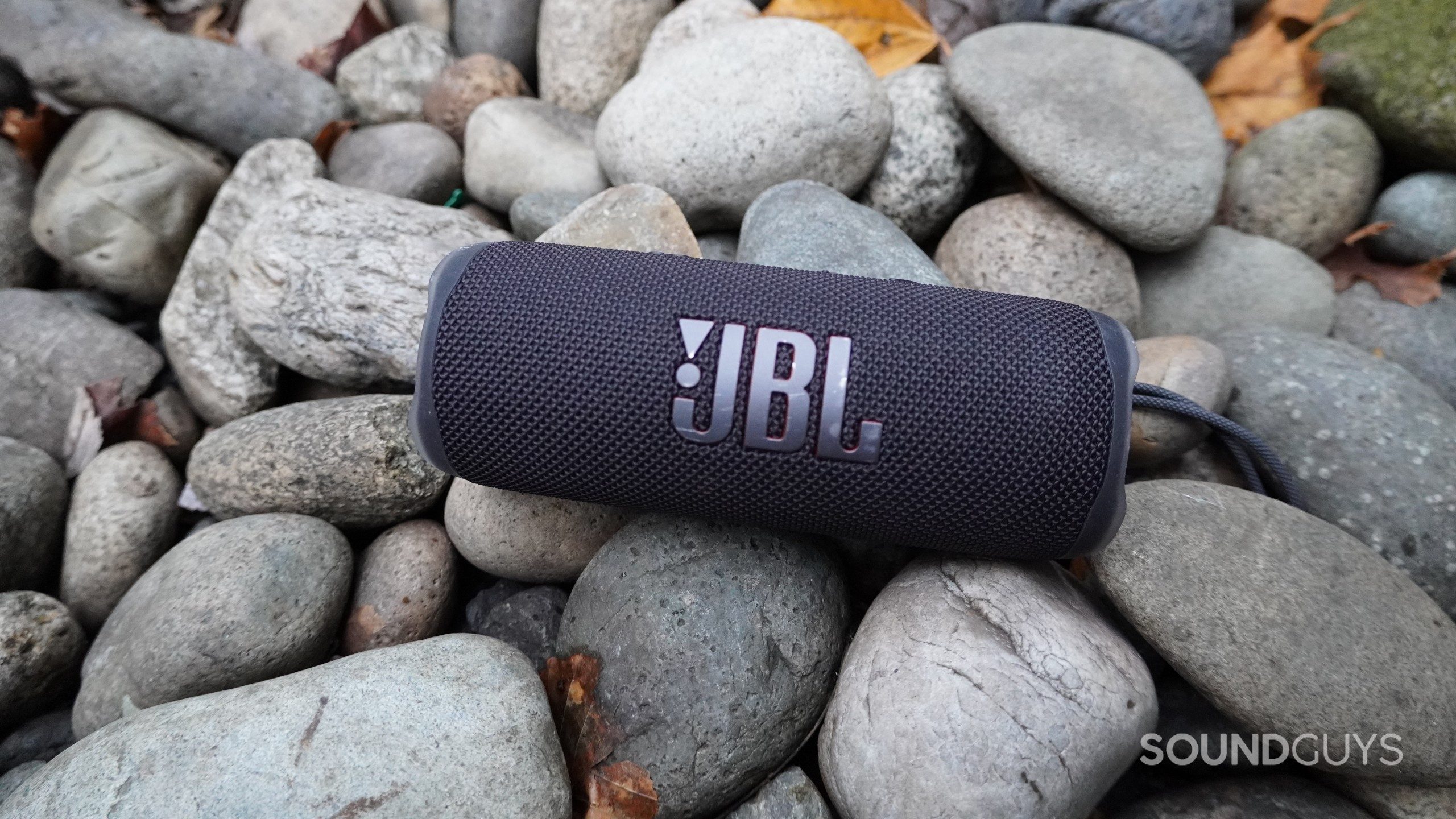 JBL Flip 6 Stones The JBL Flip 6 in black on a bed of flat stones.