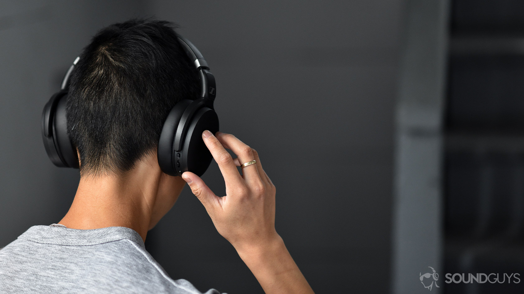 Sennheiser HD 450BT-noise canceling headphones controls 2 A picture of the Sennheiser HD 450BT noise canceling headphones worn by a woman as she adjusts the volume via the onboard controls on the right ear cup.
